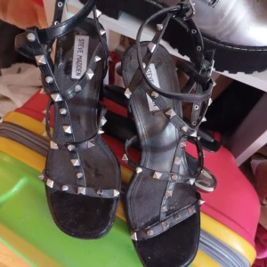 Svarta sandaler med nitar från Steve Madden - Snygga svarta sandaler från Steve Madden med nitar och klack. De har en öppen tå och flera remmar som ger en cool look. Perfekta för att ge en edgy touch till din outfit.