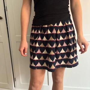 Mönstrad kjol med hjärtan - Säljer en söt kjol med hjärtmönster i svart, beige och rött. Kjolen har en elastisk midja för en bekväm passform och är perfekt för sommaren🥰Den är kort och passar bra till en enkel topp. super fin! 