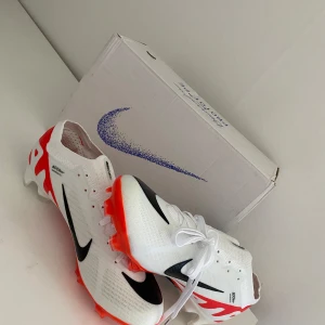 Vita och röda fotbollsskor från Nike - Varför köpa nya för 1999 kr, när man får dessa helt oanvända Snygga vita fotbollsskor från Nike med röda och svarta detaljer. Skorna har en rund tå och snörning för perfekt passform. Perfekta för fotbollsplanen med sin greppvänliga sula för bara 799