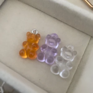 Färgglada björnhängen - Säljer tre söta björnhängen i olika färger: orange, lila och transparent. Perfekta som charmiga detaljer till ditt armband eller halsband. Varje björn har en liten ögla för enkel fastsättning.