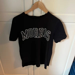 Morris T-shirt  - Säljer en svart t-shirt från Morris med stort tryck av märkesnamnet på framsidan. T-shirten är kortärmad och har en klassisk rund halsringning. Är som ny knappt använd!😁