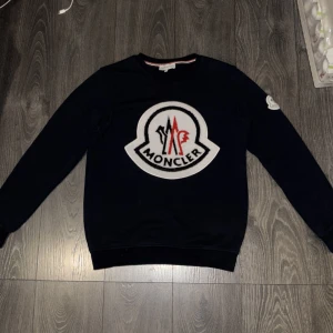 Moncler tröja - Supersnygg moncler crewneck i riktigt bra skit, endast använd 1 gång. Mjuk och tung bomull, riktig bra kvalitet - känns lyxig och sitter perfekt. Storlek: S - sitter som M. Färg: marinblå. Skick: 9,5/10 - Inga fläckar, noppor eller skador. Jag vet dock inte om den är äkta, fick den som present, därför säljer jag den lite billigare än normalt. Kolla bilderna, du ser själv att det är toppkvalitet. 💸 Pris: 1000kr (kan gå ner lite vid snabb affär). Skric vid intresse eller om du vill se fler bilder!