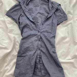 Grå kortärmad tröja med knappar - Säljer en stilren grå tröjamed korta ärmar och knappar framtill. Perfekt för en avslappnad look. Tröjan har en klassisk krage och är tillverkad i ett lätt material.