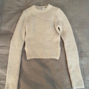 Beige stickad tröja från Zara - Säljer en stilren beige stickad tröja från Zara. Tröjan har en croppad passform och långa ärmar, perfekt för kyligare dagar. Den är mjuk och bekväm, idealisk för både vardag och avslappnade tillfällen.