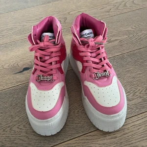 Rosa och vita sneakers från Juicy Couture - Snygga rosa och vita sneakers från Juicy Couture med hög sula och snörning. Skorna har en cool Juicy-detalj på snörena och en bekväm passform. Perfekta för att ge din outfit en färgklick! Ny skick😱 säljer då dom inte används!