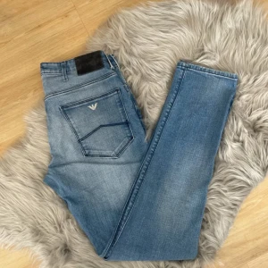 Blå jeans från Emporio Armani - Snygga blå jeans från Emporio Armani med klassisk femficksdesign och logotypdetalj på bakfickan. Jeansen har en normal passform och är tillverkade i denim med en lätt tvättad look. Perfekta för en stilren vardagslook.