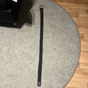 Svart flätat bälte från Jack & Jones - Snyggt svart flätat bälte från Jack & Jones med silverfärgat spänne. Perfekt för att ge en stilren touch till din outfit. Bältet är i en klassisk design som passar till många olika stilar.