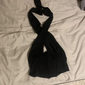 Svart topp från Gina Tricot - Snygg svart topp från Gina Tricot som man knyter runt halsen.  Använd 1 gång och passar både storlek xs och s