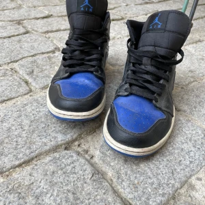 Nike Air Jordan 1 mid royal blue - Snygga Nike Air Jordans i en cool kombination av svart och blått. Väldigt använda men fortfarande snygga säljer billigt !!