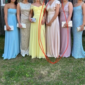 Champagnefärgad långklänning med volangdetaljer - Elegant champagnefärgad tvådelad långklänning. Med en lång kjol och en topp med v-ringad design och volangdetaljer på axlarna som går att knyta på olika sätt. Klänningen har en omlottstil som ger en smickrande passform. Perfekt för balen t.ex🤩 Jag köpte min i en lite butik i Grekland 🇬🇷 för ungefär 2300kr