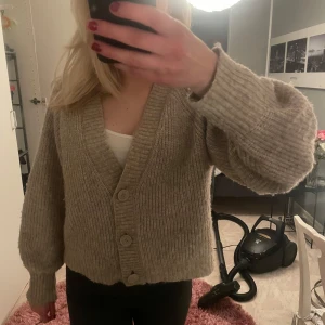 Beige stickad kofta - Säljer en mysig beige stickad kofta med v-ringning och knappar framtill. Så snygg til våren!! Köpt på Gina