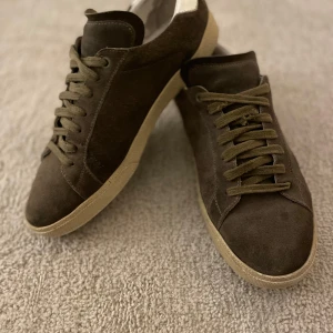 Bruna mockasneakers från Saint Laurent - Snygga bruna sneakers i mocka från Saint Laurent med vit häl och beige sula. Har änvant en sommar bara och inte mer och är hyvsat nya och i mycket bra skick, kostar 6000kr ny pris.