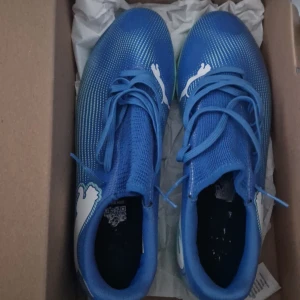 Puma future  - Snygga blå fotbollsskor från Puma med vit logga och turkos sula. Skorna har en strumpliknande passform och snörning för optimal komfort och stöd. Perfekta för inomhusspel med en stilren design. OM DU ÄR INTRESSERAD SKRIV TILL MIG SÅ SKICKAR JAG BILDER JAG HAR FAKTURAN, BOXEN OCH JAG HAR ENDAST ANVÄNT DEM 2 GÅNGER DEM ÄR HELT RENA. PRISET KAN DISKUTERAS.