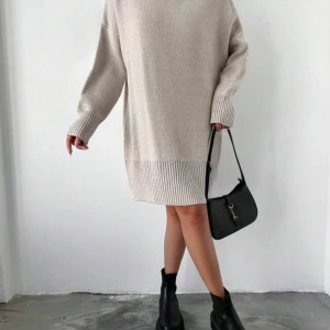 Beige stickad klänning - Säljer en mysig beige stickad klänning med långärmad design. Klänningen har en lös passform och ribbade detaljer vid ärmslut och nederkant. Använd 1-2 gånger. Onesize