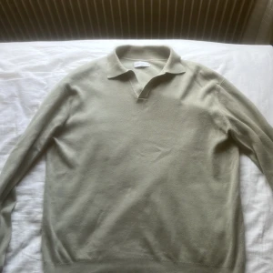 Grön pikétröja från These Glory Days - Säljer en stilren grön pikétröja från These Glory Days. Tröjan har långa ärmar och en klassisk krage med v-ringning. Perfekt för en avslappnad men ändå snygg look. Passar bra till både jeans och chinos. Perfekt nu inför kyligare dagar i vår och sommar. Tröjan är storlek s men kan passa de som bär m också.