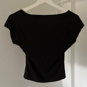 Svart kortärmad topp - Säljer en stilren svart topp med korta ärmar och en djup urringning i ryggen. Perfekt till sommaren🩷