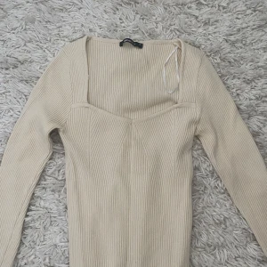 Beige ribbad tröja från Gina Tricot - Säljer en stilren beige ribbad tröja från Gina Tricot. Tröjan har en v-ringad design och långa ärmar, perfekt för en chic look. Passar bra till både jeans och kjol. Perfekt för höst och vår! Tröjan har en liten fläck på armen, som knappast syns på! Nypris är runt 300kr skulle jag gissa.
