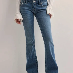 Blå bootcut jeans från True Religion - Snygga blå jeans från True Religion med klassiska kontrastsömmar och ikoniska bakfickor. Modellen har bootcut-ben och normal midja. Jeansen är i stretchigt denim som sitter skönt och ger en schysst siluett. Köpte olika storlekar och båda var för stora. Skriv privat om ni vill ha fler bilder 