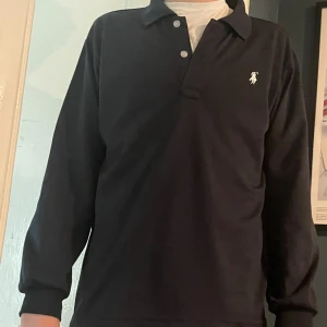 Marinblå  pikétröja från Polo Ralph Lauren - Superstilig pike från Ralph Lauren i storlek M men som kanske kan funka för S också. Inga deffekter på tröjan och har ni funderingar är det bara att höra av sig! Nypris:1500kr