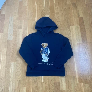 Marinblå hoodie Polo Ralph Lauren - Säljer en riktigt fet och eftertraktad marinblå hoodie från Polo Ralph Lauren med ikoniska Polo Bear-trycket🐻✨. Storleken passar som XS (L 14-16) 
