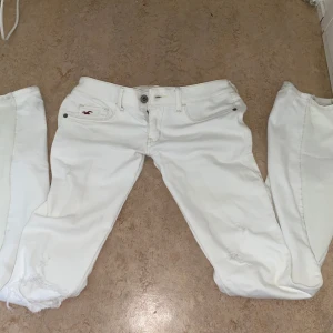 Low waist bootcut jeans - 2000s low waist!! Snygg bootcut som nästan är samma nyans som resten av jeansen (dem är insydda i lår och är sydda mer lowwaist) dem har snygga slitningar här och var och ett hål på vänster knä. Från hollister då loggan syns på framsidan och på baksidan💕 Använd ca 2ggr, ser ut som nya.