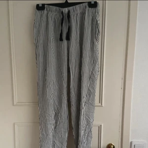 Randiga byxor med snörning - Snygga och bekväma byxor med svartvita ränder och dragsko i midjan. Perfekta för en chill stil och har fickor på sidorna. Lätta och luftiga, passar bra till både t-shirt och hoodie.