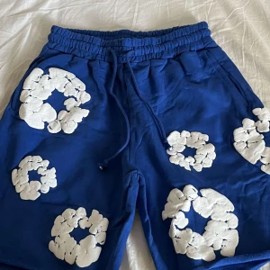 Blå shorts från Denim Tears med tryck - Blå shorts från Denim Tears med elastisk midja och snörning. De har unika vita tryck i form av cirklar över hela plagget. Ingen prislapp!