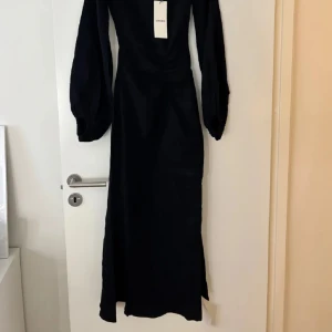 Vit långklänning Reno Dress från Adoore - Supersnygg långklänning från Adoore i modellen Reno Dress. Klänningen är vit med offshoulder och långa puffärmar. Den har en smickrande drapering vid midjan och är tillverkad i ett strukturerat tyg som ger en lyxig känsla. Helt ny aldrig använd! Denna svarta finns inte kvar på hemsidan!