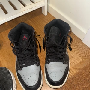 Nike Air Jordan 1 shadow red - Säljer ett par Nike Air Jordan 1 shadow red i svart och grått med klassisk röd Jumpman-logga på plösen. Skorna har snörning, rund tå och vit sula. Perfekta för dig som gillar streetwear och vill ha en ikonisk sneaker i din samling. Ena skon är ytterst lite creesad andra i princip mint.