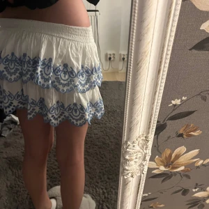 Vit volangkjol - Supersöt vit kortkjol med blått broderat  mönster från Lindex 🩷kom inte till andvåndning andvåd 2 gånger utomlands🥰