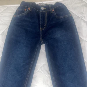 Levi's 512 Slim mörkblå jeans - Mörkblå Levi's 511 jeans med klassiska kontrastsömmar och femficksdesign. Jeansen har en rak passform och är tillverkade i slitstarkt denim med snyggt läderpatch bak i midjan. Perfekta för dig som gillar en tidlös och clean look.