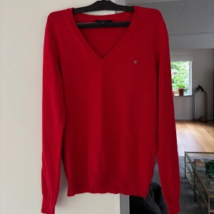 Röd v-ringad tröja från GANT - Snygg röd v-ringad tröja från GANT i 100% bomull. Klassisk modell med ribbade muddar och liten broderad logga på bröstet. 