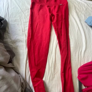 Röda tights aimn  - Snygga röda leggings med bred ribbad midja som sitter skönt och ger en tight passform. Perfekta för träning eller chill, i mjukt och stretchigt material som följer kroppen. Färgen är klar röd och modellen är klassiskt enkel utan fickor eller detaljer.