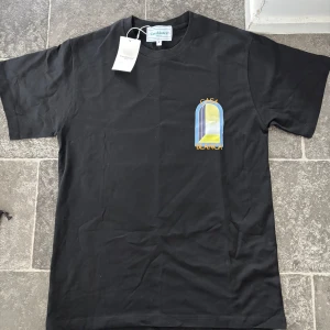 Casablanca T shirt - Svart t-shirt från Casablanca med färgglatt grafiskt tryck fram och bak i blått, gult och vitt. T-shirten har rund hals, korta ärmar och är gjord i mjuk bomull. Perfekt för dig som gillar streetwear med en twist och vill sticka ut med cool design. tveka inte att höra av er vid mer bilder. Vid snabb köp så hittar vi något fint som passar båda 😊