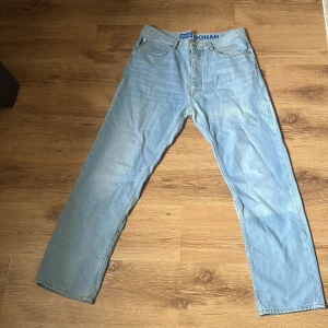 Ljusblå raka jeans från Hugo Boss  - Säljer ett par ljusblå jeans från Hugo i modellen Jonah. Jeansen har klassisk femficksdesign, raka ben och normal passform. Snyggt blått Hugo-märke baktill i midjan och diskreta slitningar för en avslappnad look. Perfekta till sneakers och hoodie.