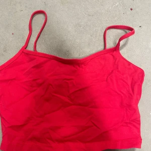 Röd croppad linnetopp från SHEIN - Säljer en röd croppad linnetopp från SHEIN med tunna axelband. Perfekt för sommaren och enkel att matcha med både jeans och kjol. Toppens material känns mjukt och lätt mot huden.