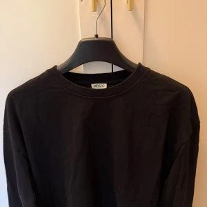 Svart långärmad tröja från Kenzo - Säljer en svart långärmad tröja från Kenzo med rund halsringning. Tröjan har en stor vit Kenzo Paris-logga tryckt på ärmen.