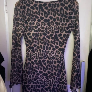 Leopardmönstrad långärmad klänning - Säljer en snygg långärmad klänning med leopardmönster. Klänningen har en djup rygg och är figurnära i modellen. Materialet känns stretchigt och bekvämt, perfekt för dig som vill sticka ut med ett djuriskt mönster.