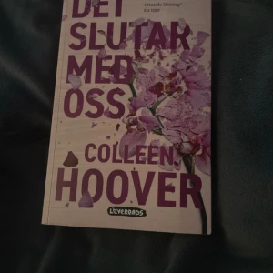 Det slutar med oss - Säljer boken 'Det slutar med oss' av Colleen Hoover, utgiven av Lovereads. Omslaget är beige med lila text och blommotiv. Boken är en roman om kärlek, relationer och svåra val, och är en New York Times bästsäljare.