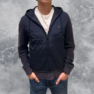 Ralph Lauren Cardigan Jacka blå - •Ralph Lauren Cardigan Hoodie Mörk Blå. Skick: 7-8/10, Inga skador (solblekt). Storlek: S. Modell: 173 cm, 65 kg. Sitter bra på modellen på bild! Authentic: ✅, QR Kod finns även i plagget! Hör av dig vid frågor eller funderingar, mvh Hessler’s;)