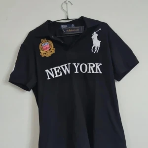 Svart pikétröja från Polo Ralph Lauren Chief Keef Polo New York - Säljer en svart pikétröja från Polo Ralph Lauren Chief Keef Polo korta ärmar och klassisk krage. Perfekt för dig som gillar sportig och stilren look