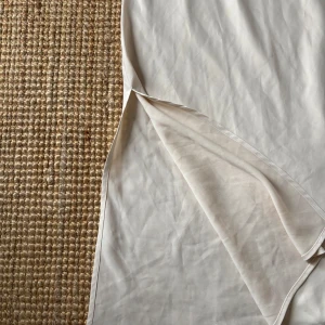 Vit långkjol från BikBok - Säljer en super fin vit/ beige långkjol från BikBok i slätt material. Kjolen har en rak passform och går ner till vaderna. Den är i storlek xs men passar även s. 