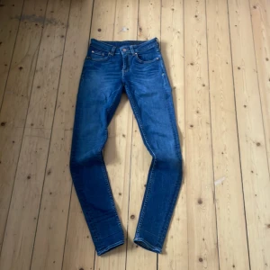 Blå jeans från Tiger of Sweden - Snygga blå jeans från Tiger of Sweden med klassisk femficksdesign och läderpatch bak i midjan. Jeansen har raka ben och normal passform, perfekta till vardags. Tidlös modell i slitstarkt denimtyg.