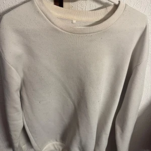 Vit sweatshirt med rund hals - En basic vit sweatshirt med rund hals och långa ärmar. Perfekt för en enkel och stilren look. Mjuk och bekväm, passar till det mesta i garderoben.