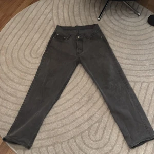 Grå jeans från Sweet Skateboarding Company - Säljer ett par grå jeans från Sweet Skateboarding Company. Byxorna har klassisk femficksdesign, raka ben och loose passform. Tillverkade i 100% bomull och har en snygg läderpatch bak i midjan.