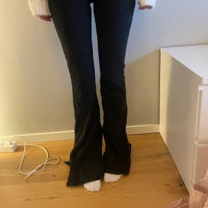 Svarta bootcut jeans - Säljer ett par svarta bootcut jeans med klassisk femficksdesign och knappgylf. Jeansen har en låg midja och är i stretchigt material.