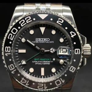 Seiko GMT-Master II klocka - Snygg Seiko GMT-Master II med svart urtavla, datumfönster och tydliga indexmarkeringar. Klockan har en tvåfärgad vridbar bezel och robust boett i silverfärgat stål. Perfekt accessoar för dig som gillar klassisk design och funktion.