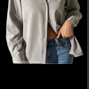 Beige satinblus med knappar - Snygg beige blus i satin med klassisk krage och knäppning framtill. Långa ärmar med breda muddar och en lätt glansig finish som ger en lyxig känsla. Perfekt att styla till jeans eller kjol för en trendig look.