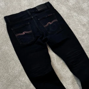 Nudie jeans Lean Dean (limited edition) - Tja! Säljer nu dessa sjukt feta svarta Limited Edition Nudie jeans utav modellen ”Lean Dean”! Jeansen är utav en speciallutgåva där swooshen på bakfickan är i röda färger vilket gör dem väldigt unika! Bra skick, slitna på ett snyggt sätt! Size 29/30. Skriv vid funderingar!
