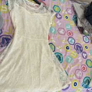 Vit spetsklänning från Rosemunde copenhagen  - Superfin vit kortklänning från Rosemunde med blommig spets och transparenta partier upptill. Klänningen har korta ärmar och en söt, feminin look med mjukt foder under spetsen. Perfekt för dig som gillar romantisk stil och detaljer.